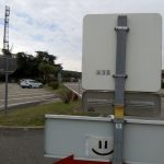 Spot d'auto-stop avec pancarte sourire et un sticker d'Hitchwiki
